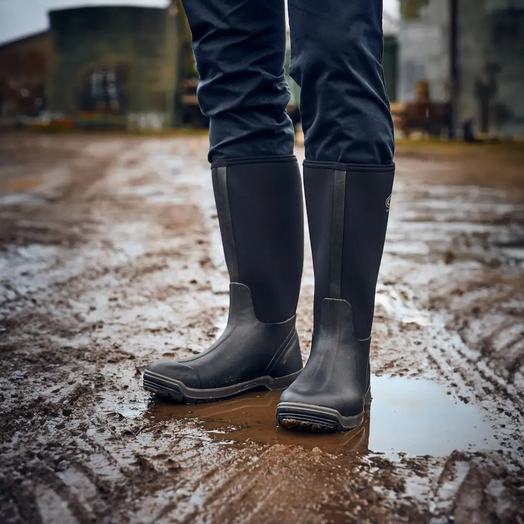 Pair of Grubs Frostline Classic 5.0 Wellington boots in muddy terrain