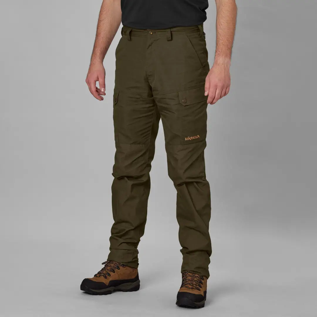 Person wearing Olive Green Harkila Asmund Trousers made from waxed canvas outdoors