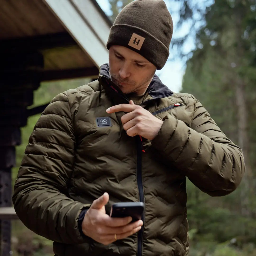 Person in a puffy Harkila Clim8 Insulated Jacket using a smartphone with power bank