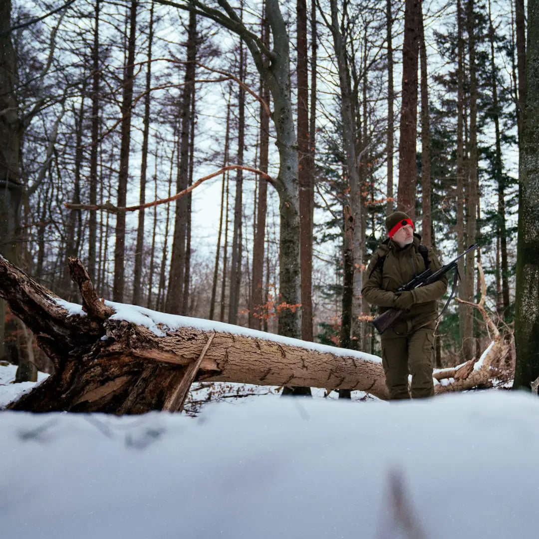 Person in winter clothing by a fallen tree wearing Harkila Driven Hunt HWS Insulated Jacket