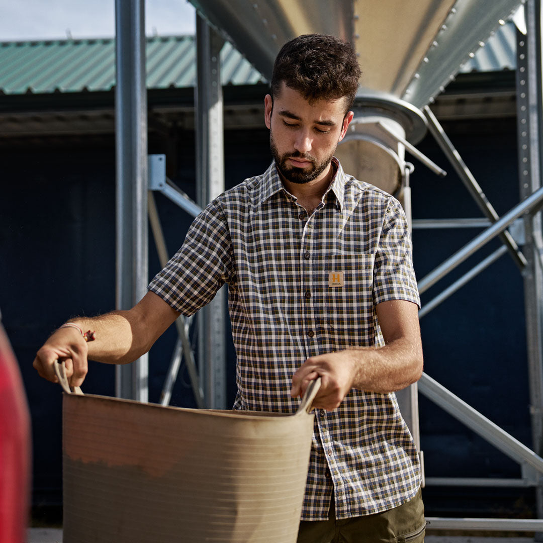 Man holding a bucket wearing a Harkila Fjell Short Sleeve Shirt outdoors