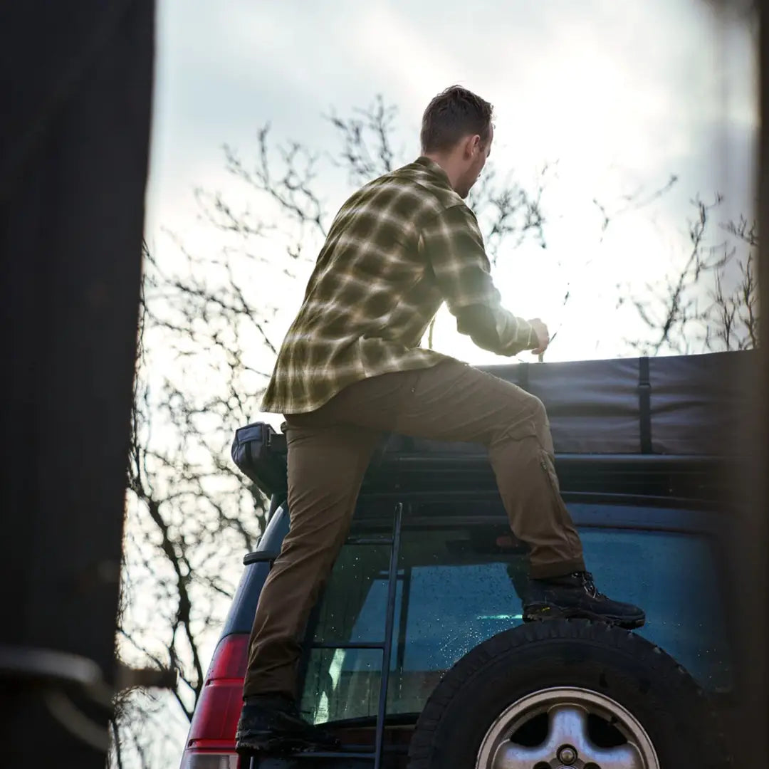 Person climbing onto a vehicle wearing a stylish Harkila Folke Shirt Jacket