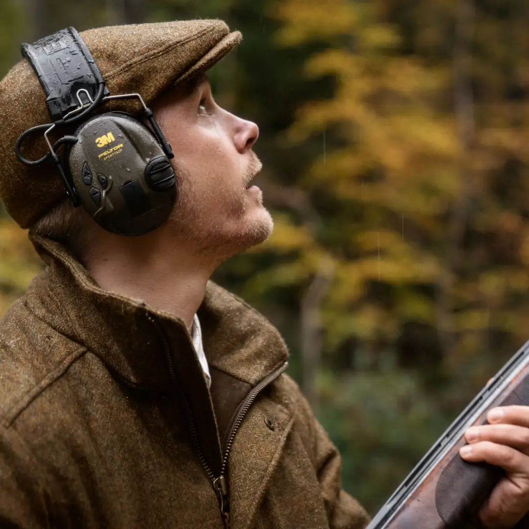 Person in hunting gear with rifle wearing a Harkila Kenmore Flat Cap