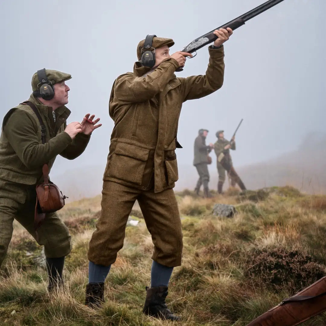 Hunter aiming shotgun skyward in Kenmore GTX Jacket that blends traditional tweed