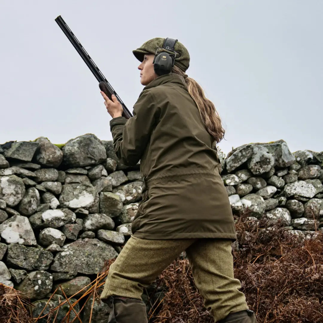 Hunter in protective gear holding a shotgun, showcasing Harkila Orton Tech HWS Jacket