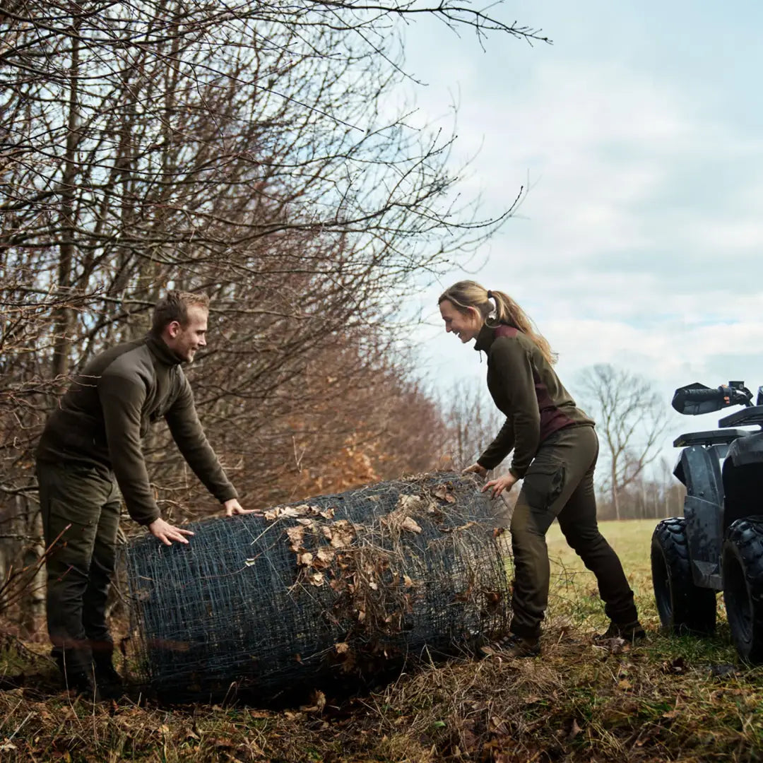 Two people lifting rolled-up turf outdoors in Harkila Ladies Scandinavian Trousers