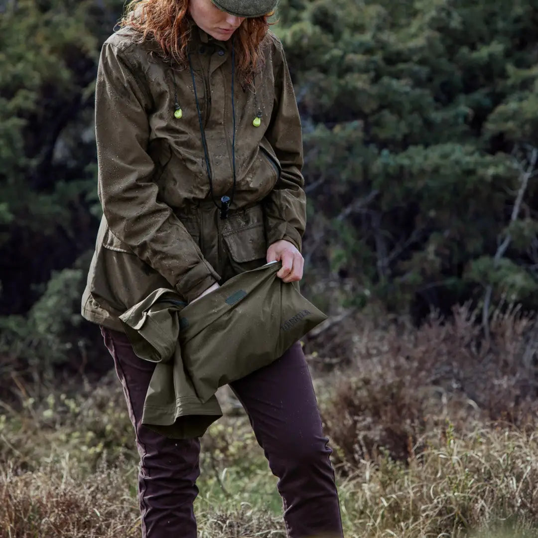 Olive green Harkila Orton Packable Lady Jacket with pockets and belt in outdoor scene