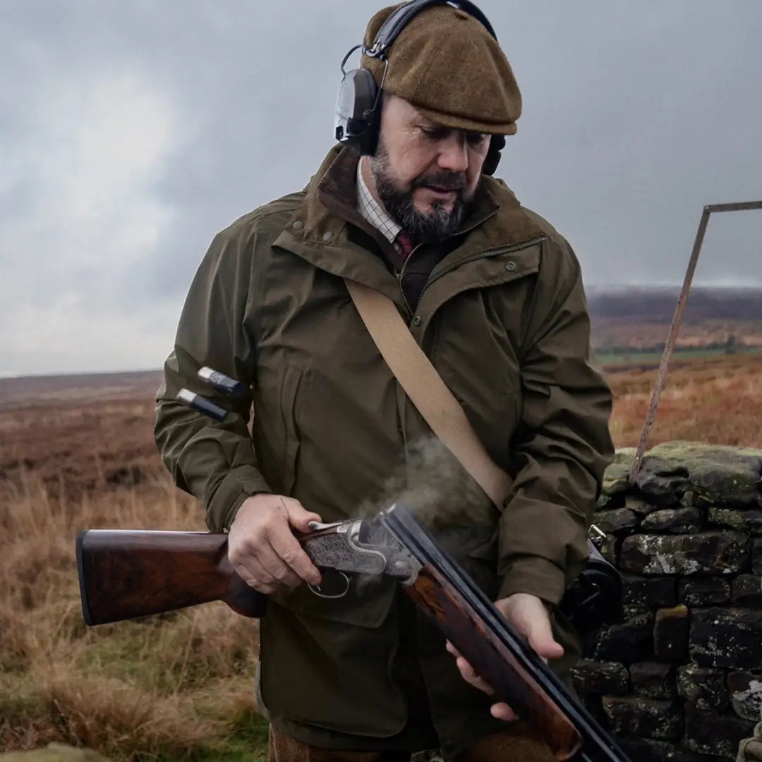 Man in a classic hunting jacket and shotgun, showcasing the Harkila Orton Tech HWS Jacket