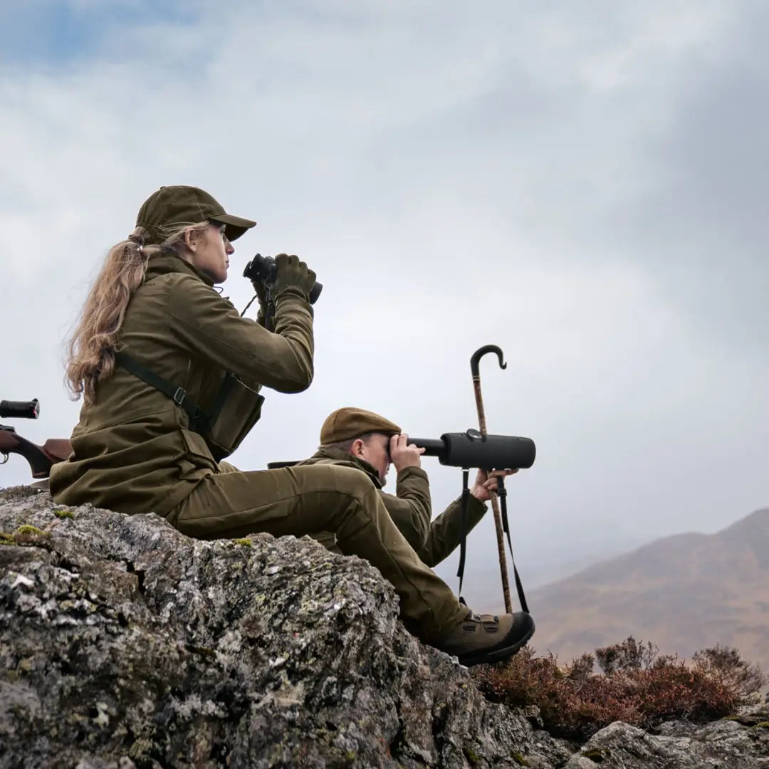 Two people in military gear using binoculars on a rocky ledge wearing Harkila Pro Hunter GTX