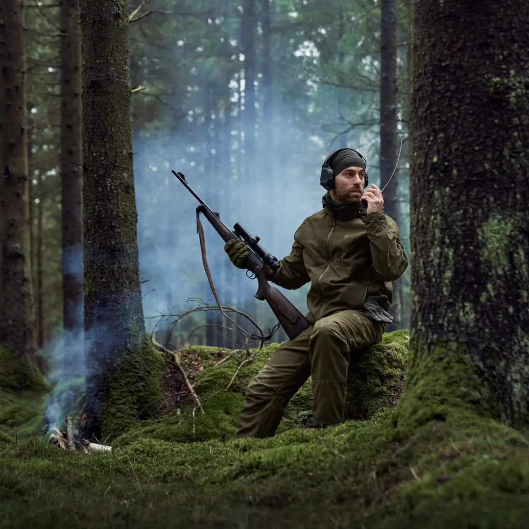 Man in military-style gear with a rifle in a misty forest wearing Harkila Pro Hunter GTX Jacket