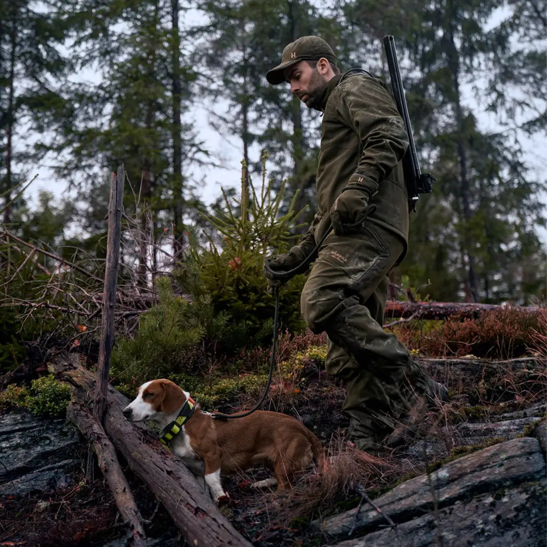 Hunter in camouflage wearing Harkila Pro Hunter Move 2.0 GTX Jacket with dog in forest