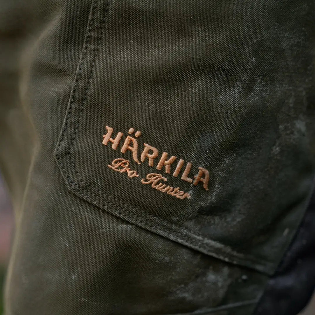 Embroidered HÄRKILA Pro Hunter logo on dark green fabric of trousers with thigh pockets