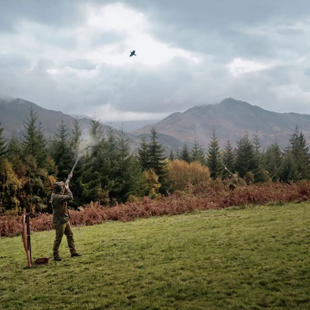 Person enjoying a shot with a Harkila Rannoch HWS Shooting Jacket in a grassy field