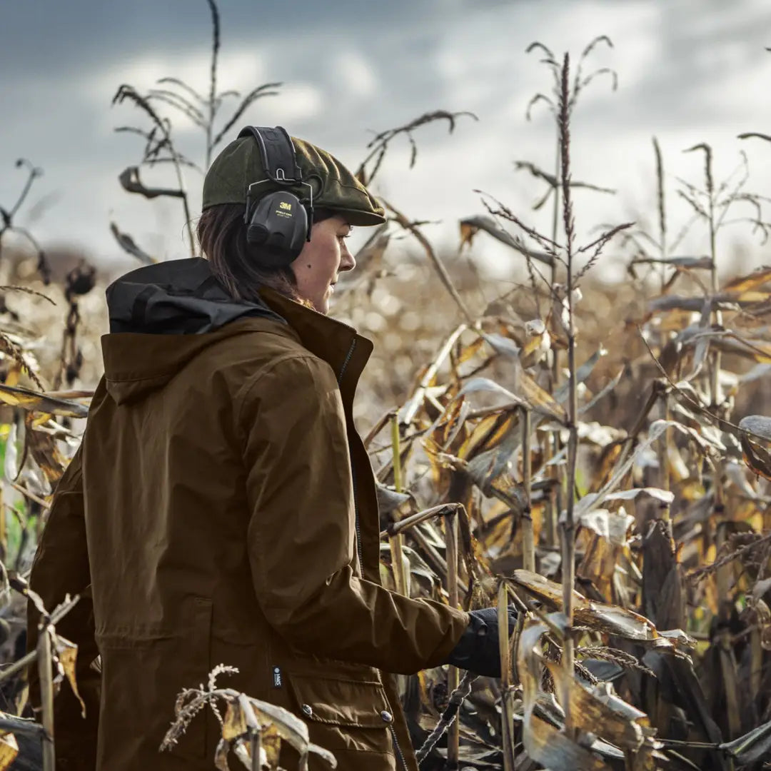 Person in brown Harkila Retrieve Lady Jacket and cap enjoying a cornfield adventure