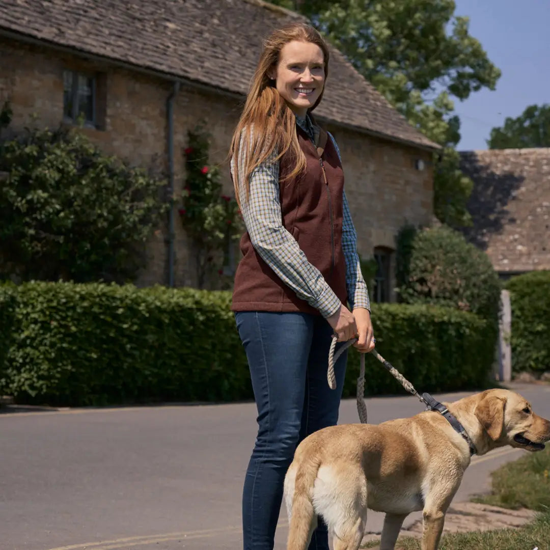 Woman in Harkila Sandhem Pro Ladies Waistcoat walking a golden Labrador on a leash