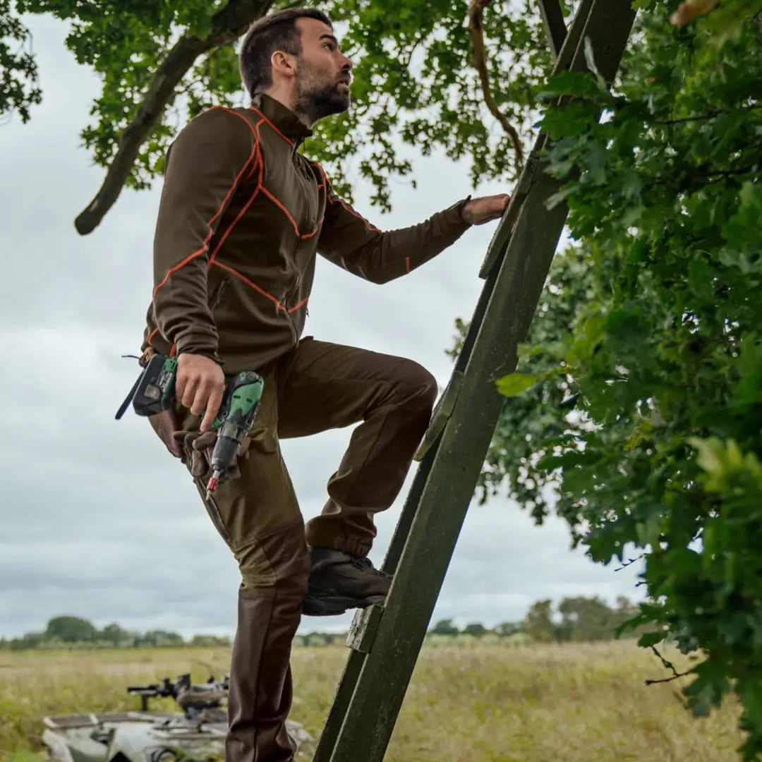 Man in outdoor gear climbing a ladder wearing Härkila Scandinavian Trousers