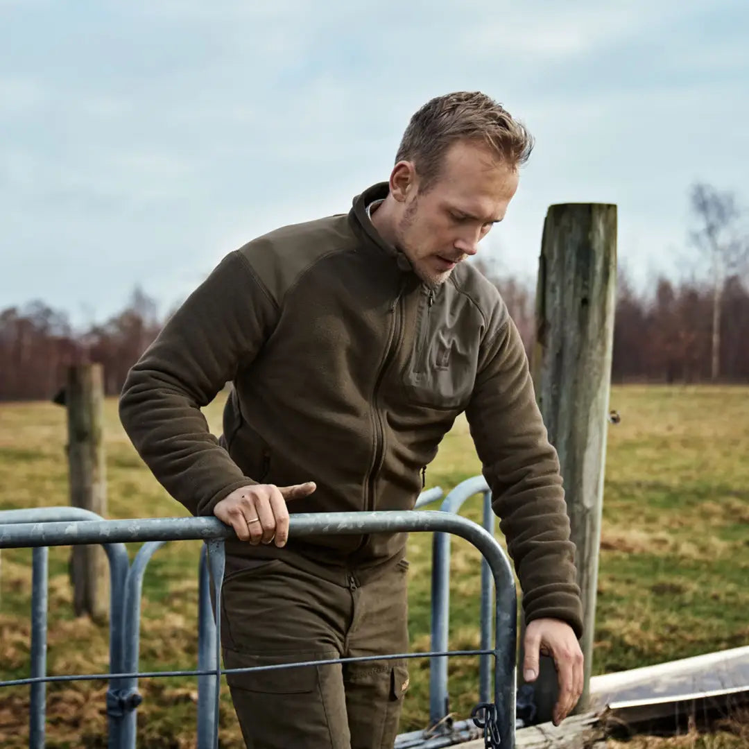 Man in brown Harkila Venjan fleece jacket with high collar by a metal gate in the countryside