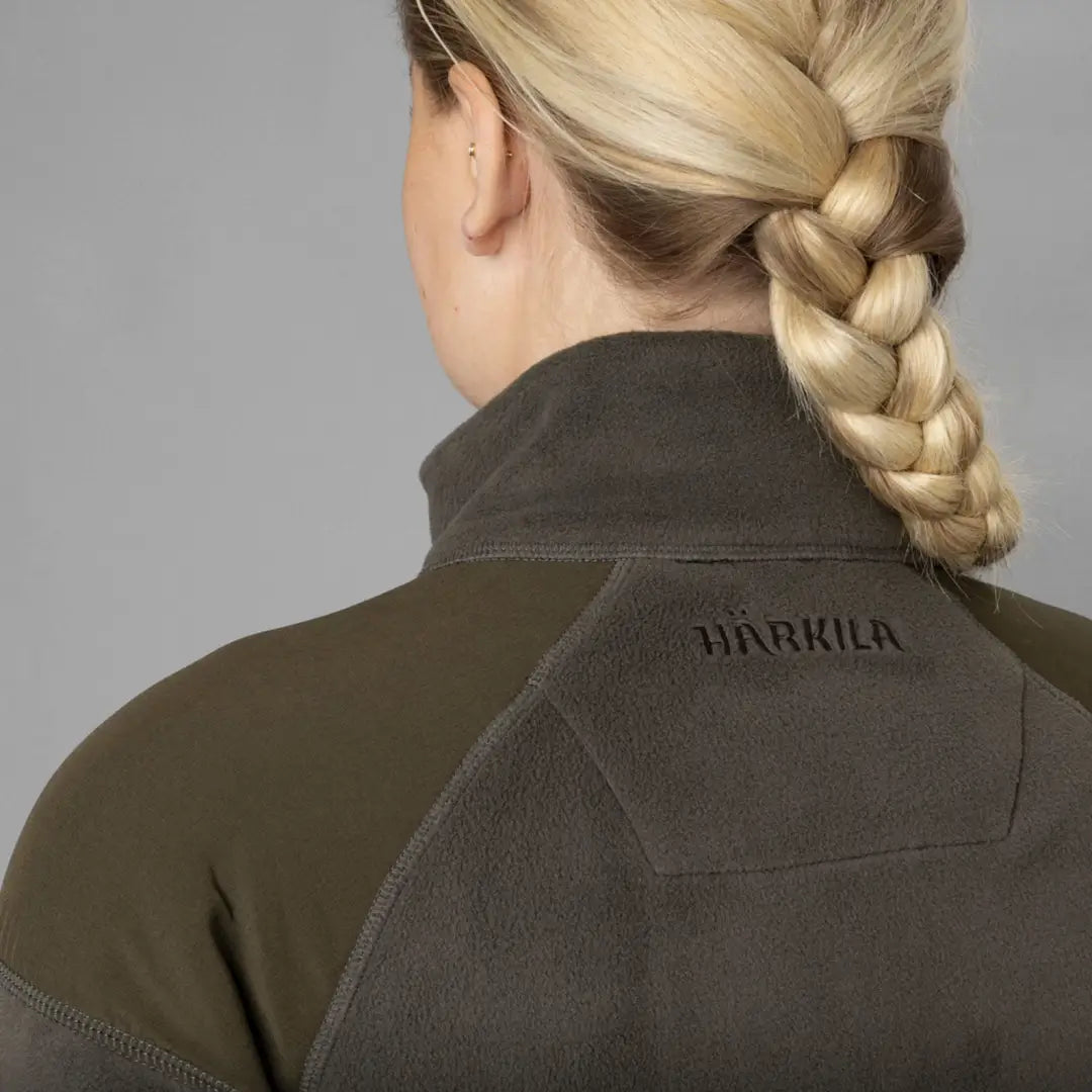 Blonde braided hair with HÄRKILA branding on dark green Vilja Ladies Fleece jacket