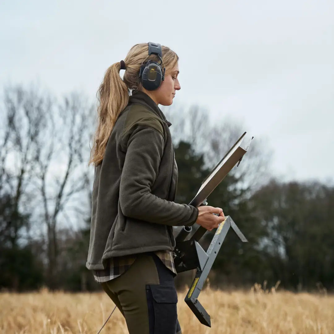 Woman in Harkila Vilja Ladies Fleece using a metal detector in a field