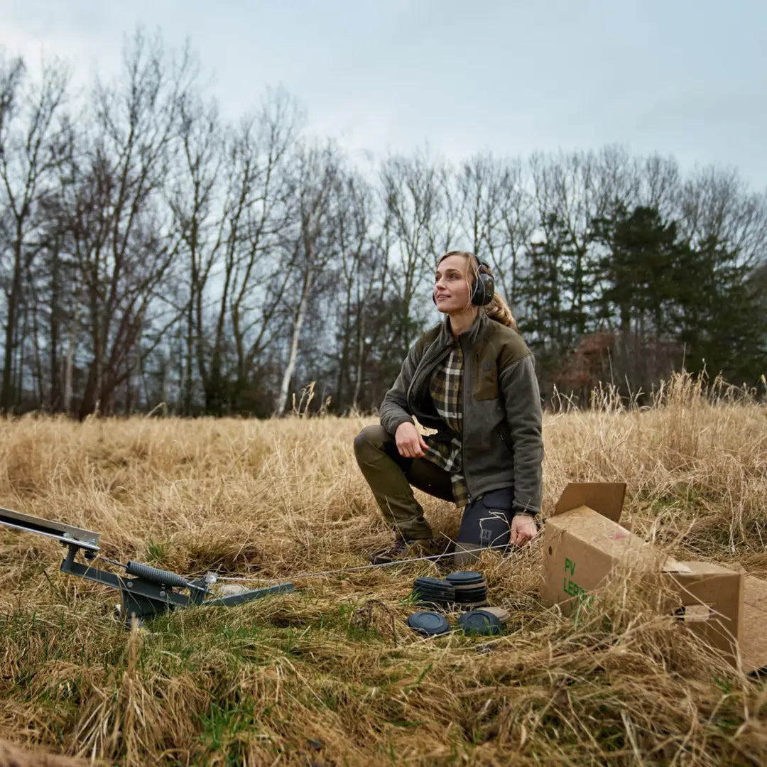 Person sitting on a box in a field with Harkila Vilja Ladies Fleece and drone gear