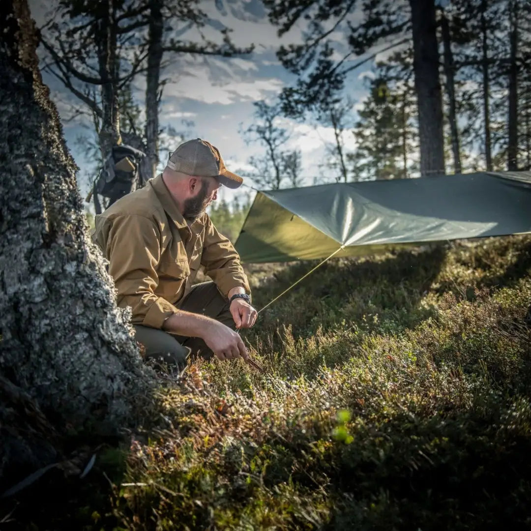 Camper using Helikon-Tex Supertarp Small for quick shelter in the forest