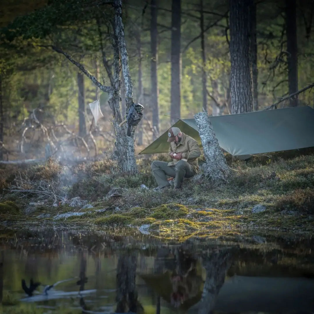 Person enjoying the Helikon-Tex Supertarp Small by a misty pond, perfect for impromptu shelter