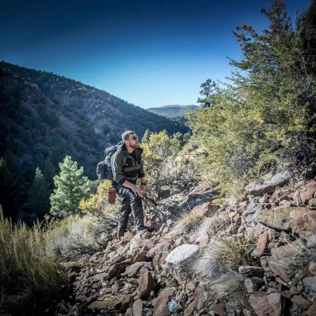 Hiker on rocky trail rocking the Helikon-Tex Woodsman Anorak Jacket for outdoor adventures