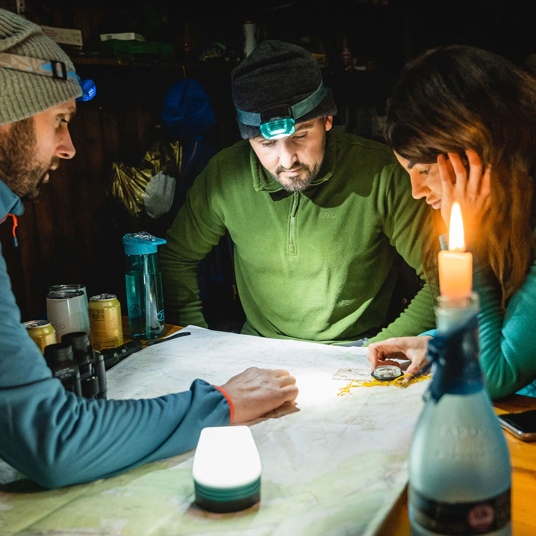 Three friends using a Highlander Hadar Rechargeable Head Torch to explore a map