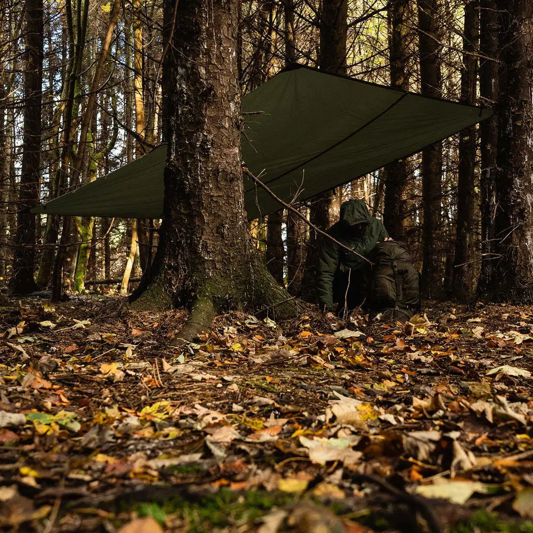 Green tarp shelter set between trees showcasing the Highlander XL Basha Tarp