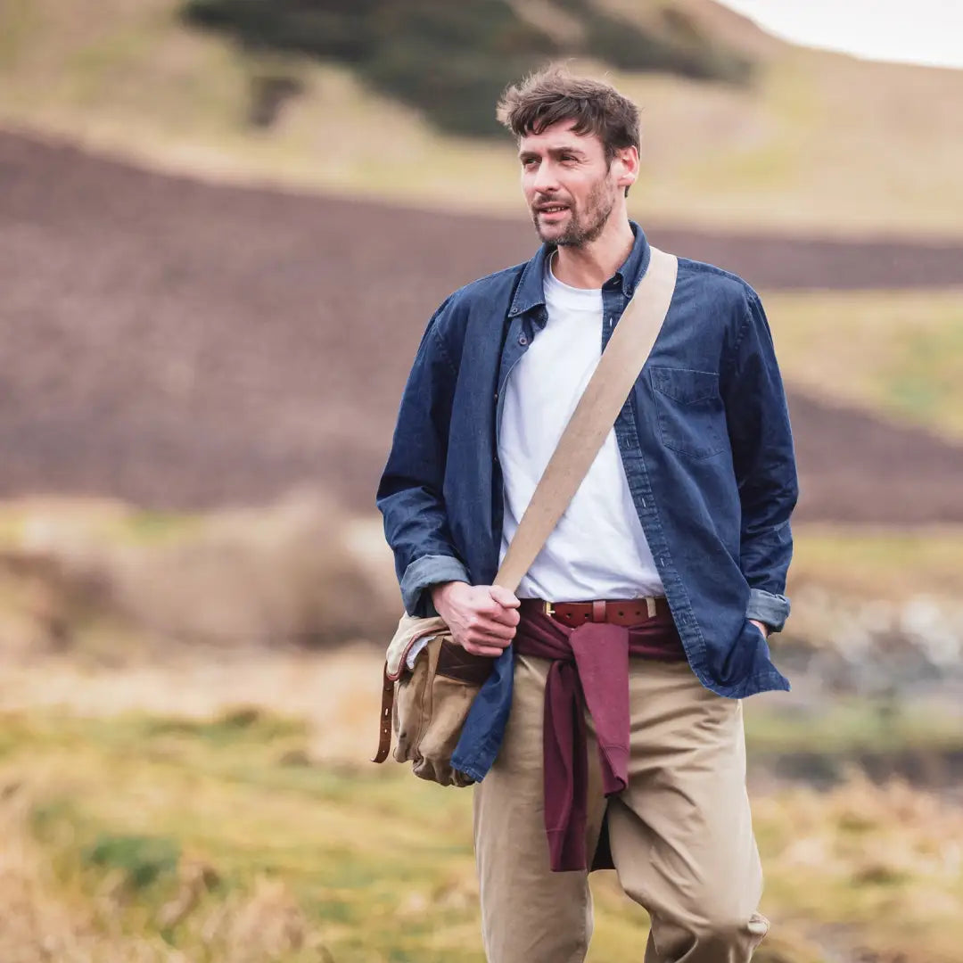 Man in a blue jacket and khaki pants with a messenger bag, showing Fife Archerfield long sleeved denim shirt