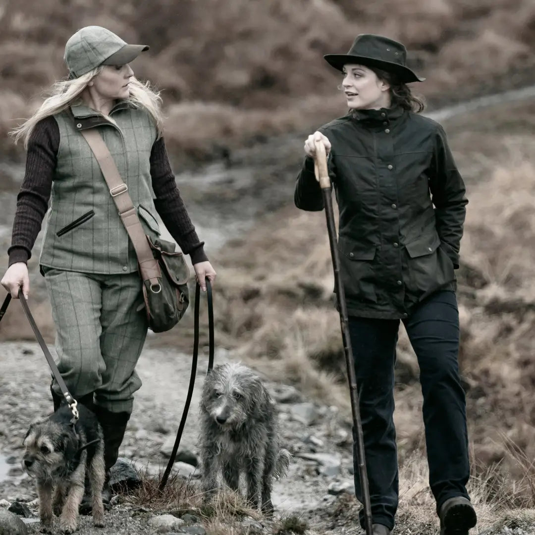 Two women in a rural setting wearing Fife Caledonia Ladies Wax Jackets walking a dog