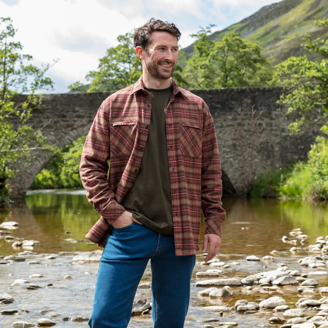 Man in plaid flannel over dark tee by stream wearing Hoggs Of Fife Countrysport Luxury Hunting Shirt