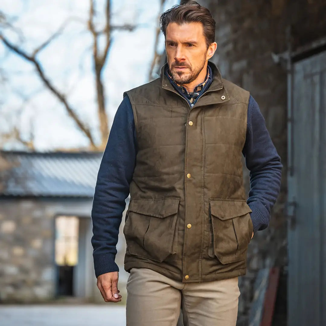 Man in a dark green quilted gilet over a navy sweater, offers soft padding style