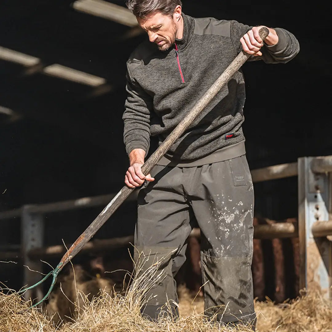 Man using a pitchfork with hay while wearing Hoggs Of Fife Green King zip knit fleece