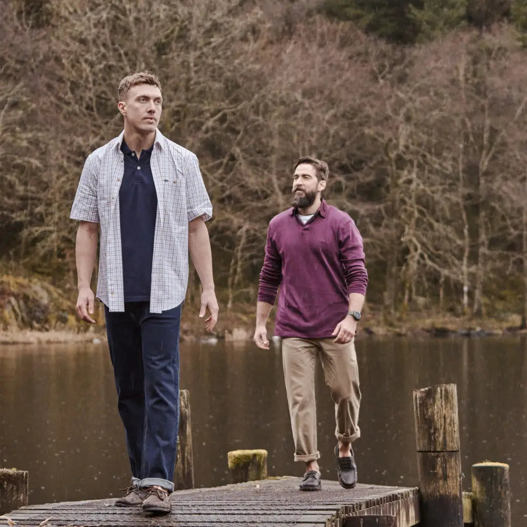 Two men stroll on a dock by a lake in a Kessock Tattersall short sleeve shirt