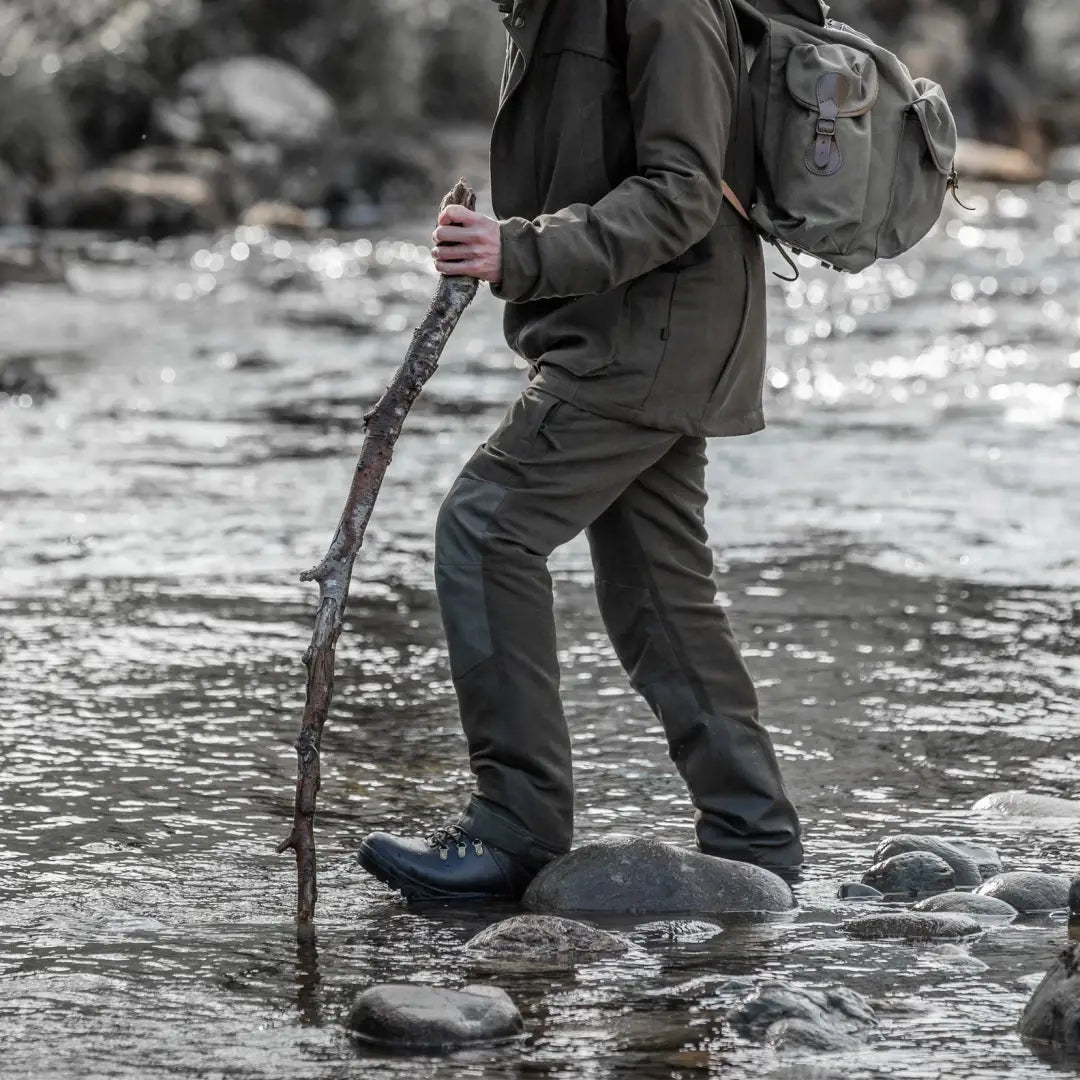 Hiker crossing a rocky stream in Fife Kincraig Waterproof Field Trousers