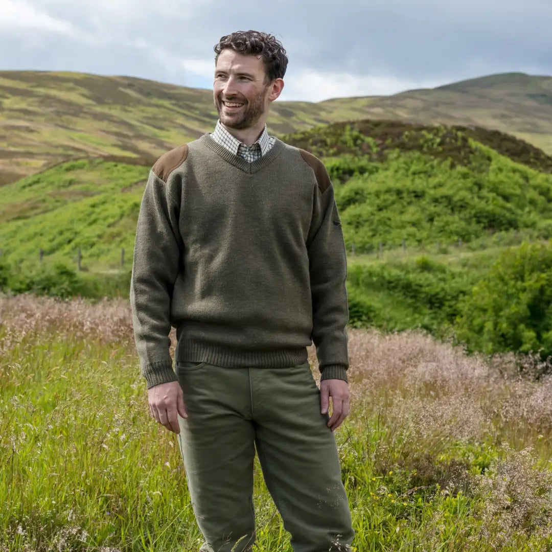 Man in olive green Fife Melrose V-Neck hunting pullover standing in a grassy field