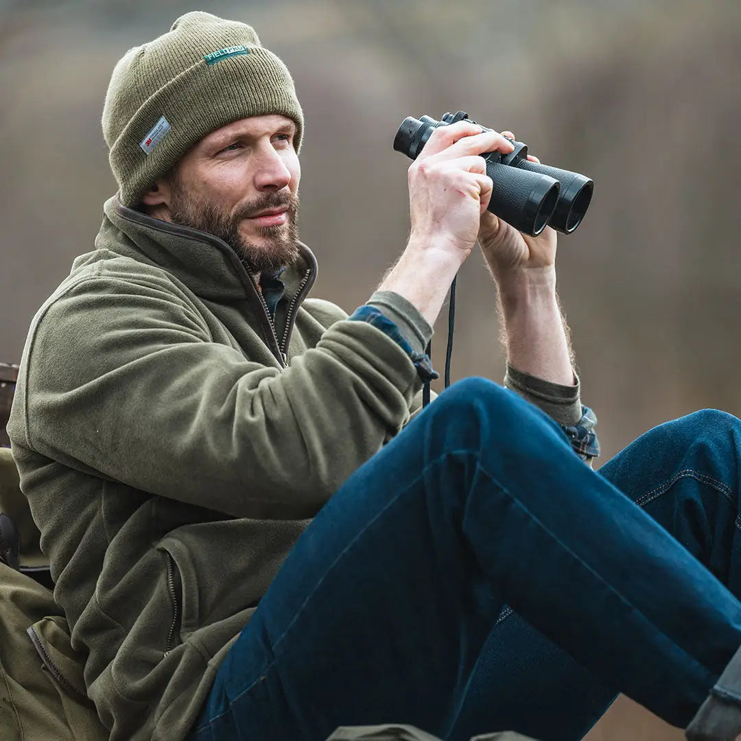 Person in outdoor clothing using binoculars while wearing Hoggs of Fife zip fleece