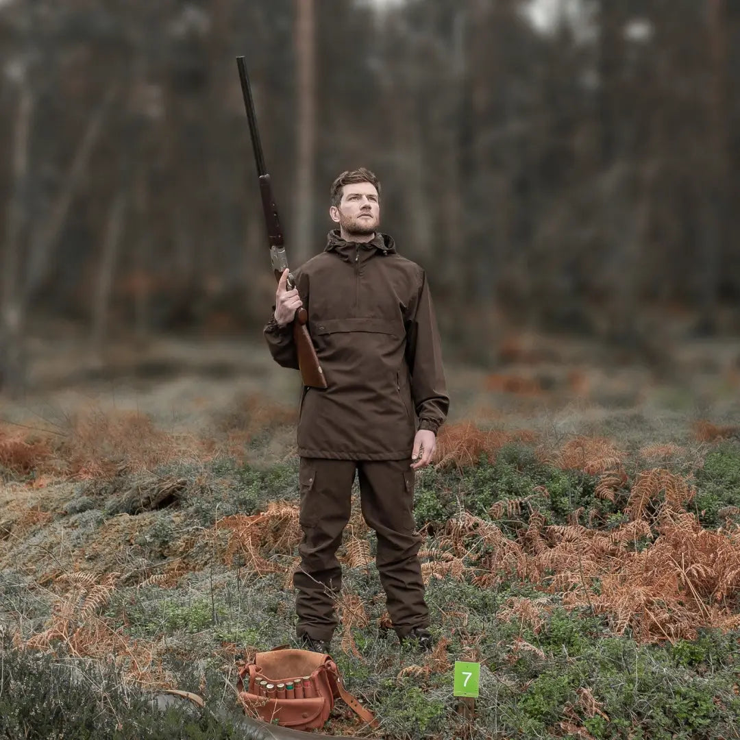 Man with a rifle in outdoor terrain wearing a Fife Struther Smock jacket