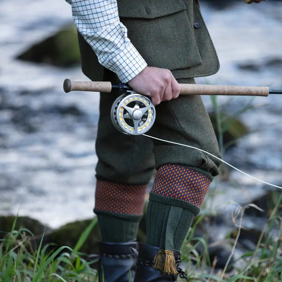 Fly fishing rod and reel in hand, showcasing House of Cheviot Tayside Socks in merino wool