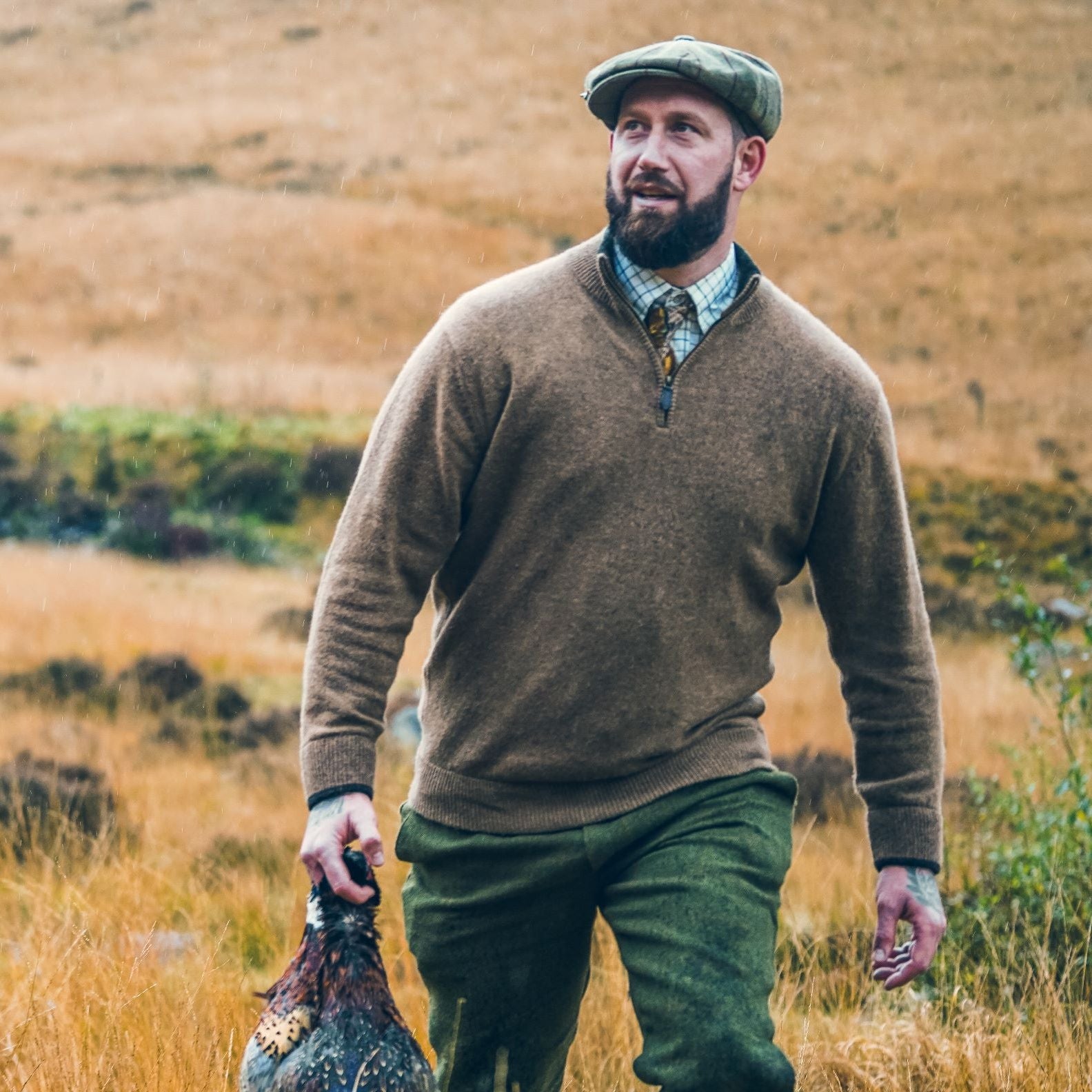 Man in tweed cap and sweater holding bird showcases Jack Pyke Ashcombe Lambwool Zipknit Pullover