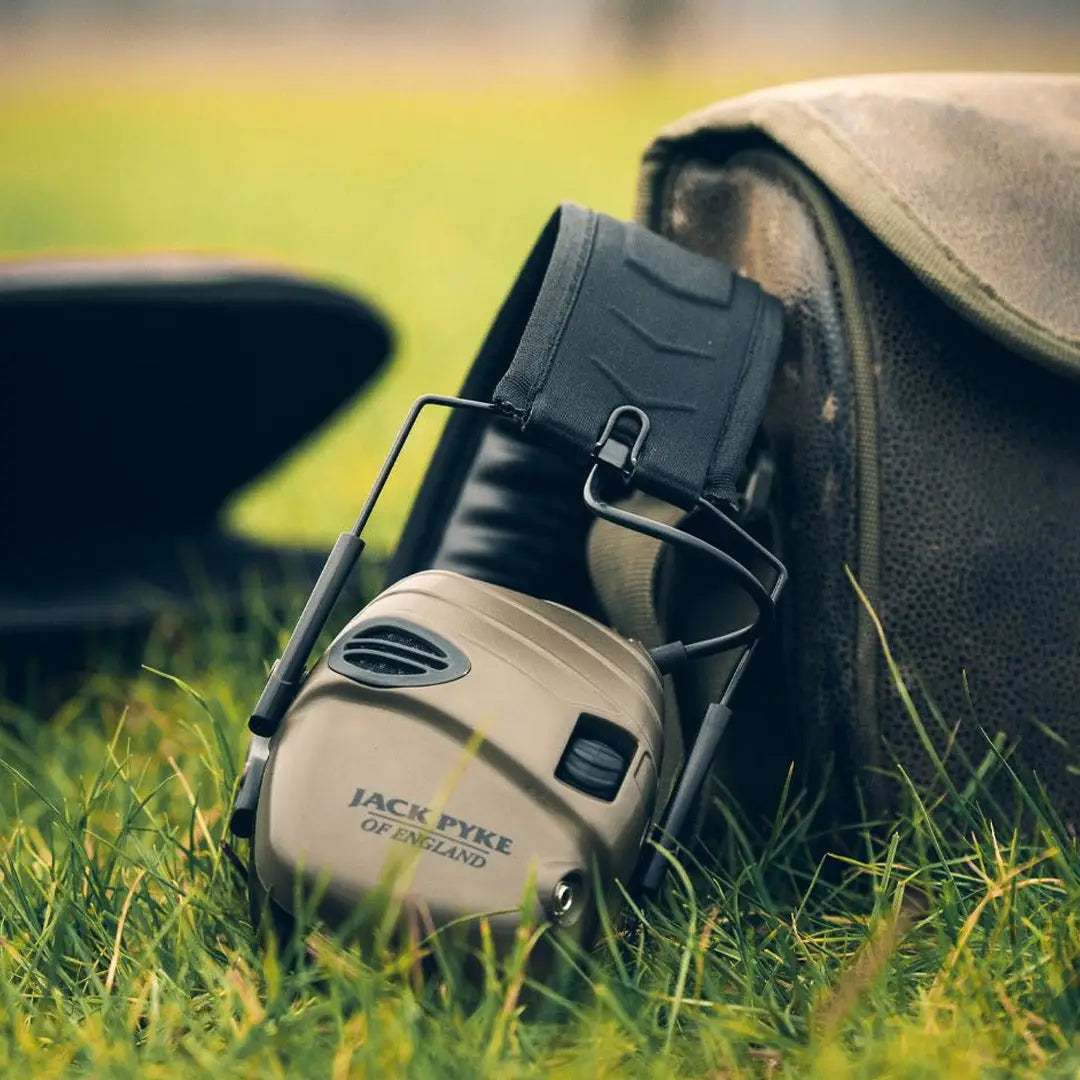 Jack Pyke Electronic Ear Defenders resting on grass, perfect for shooting and outdoor activities