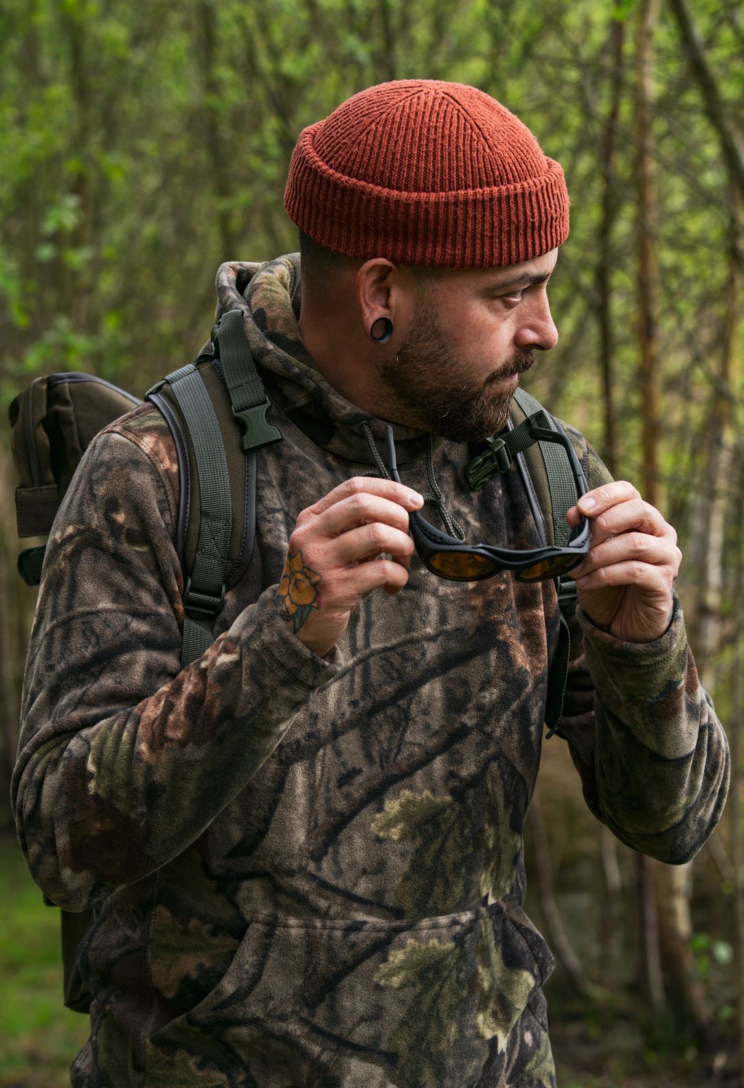 Man in camouflage hoodie holding sunglasses, showcasing Jack Pyke Fieldman Fleece