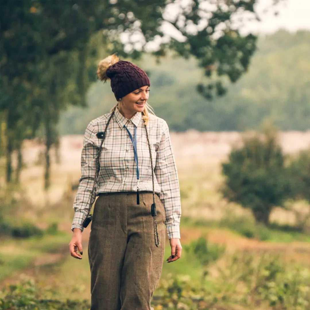 Woman in plaid Jack Pyke Ladies Countryman shirt with dark pants and knit hat outdoors