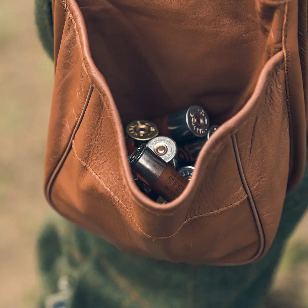 Brown leather cartridge pouch with camera lenses peeking out inside