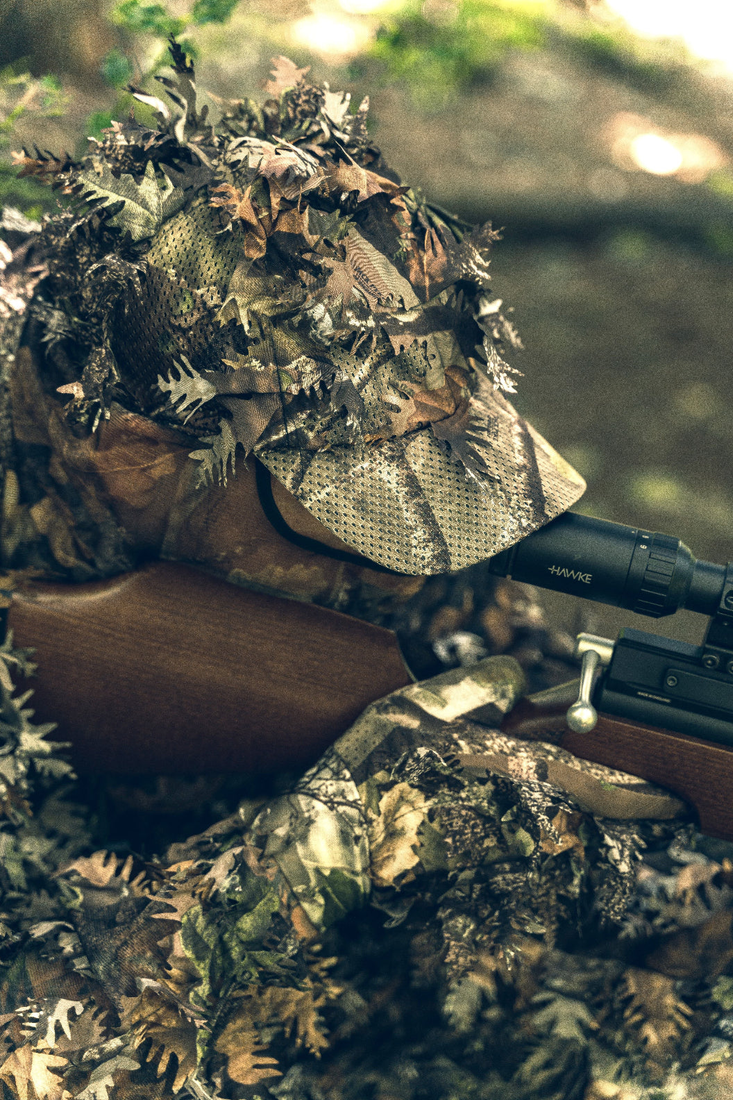 Camouflaged hunter wearing a rifle with a Jack Pyke LLCS 3D Baseball Cap