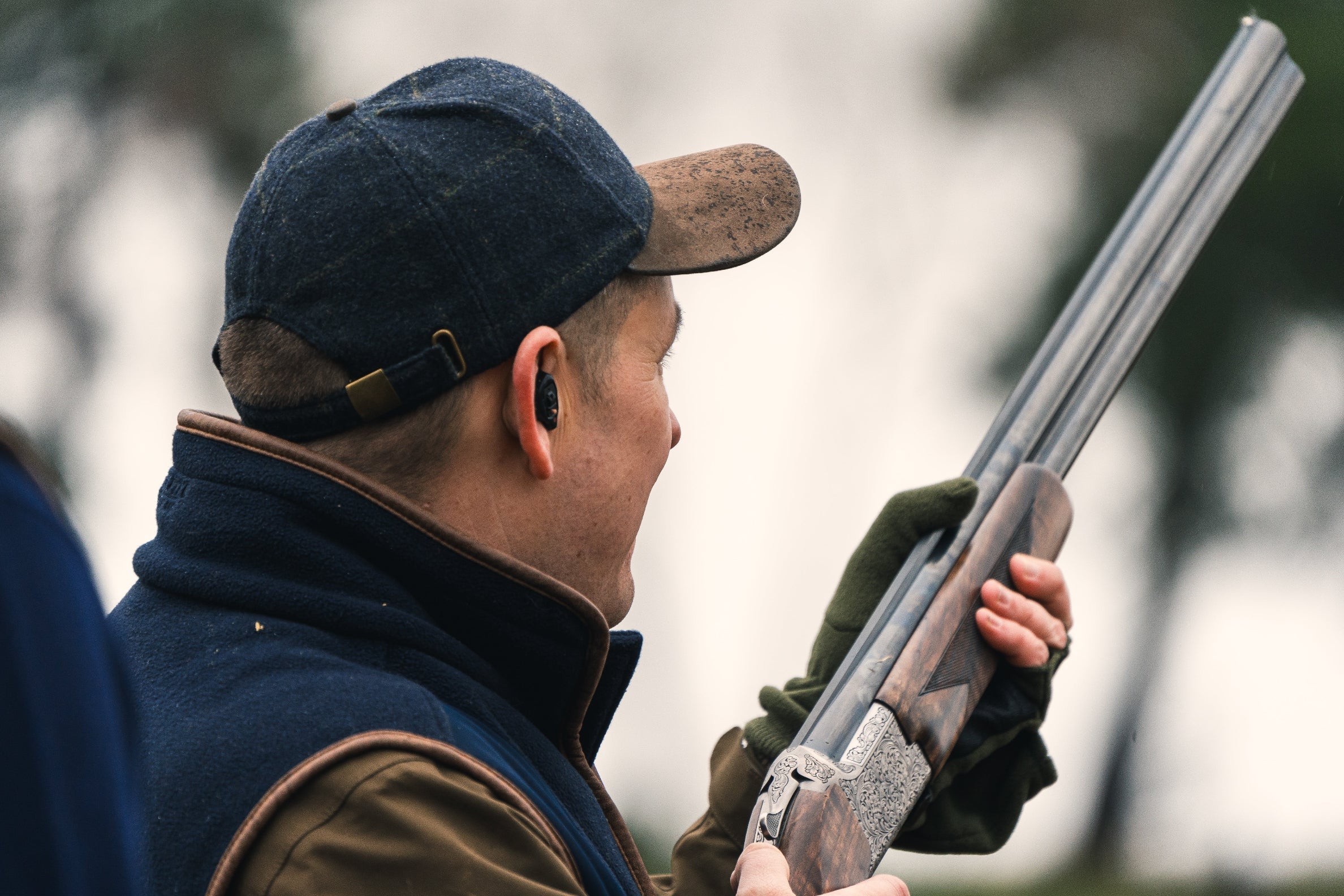 Man holding a shotgun while wearing a Jack Pyke Lowland Tweed Baseball Hat