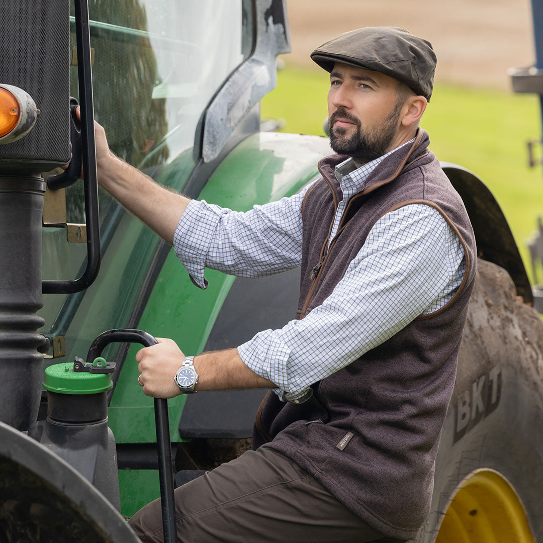 Man in tweed cap on tractor wearing Jack Pyke Melange Fleece Gilet Brown