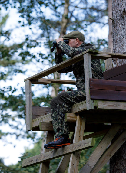 Camouflaged man in tree stand wearing Jack Pyke softshell jacket with binoculars