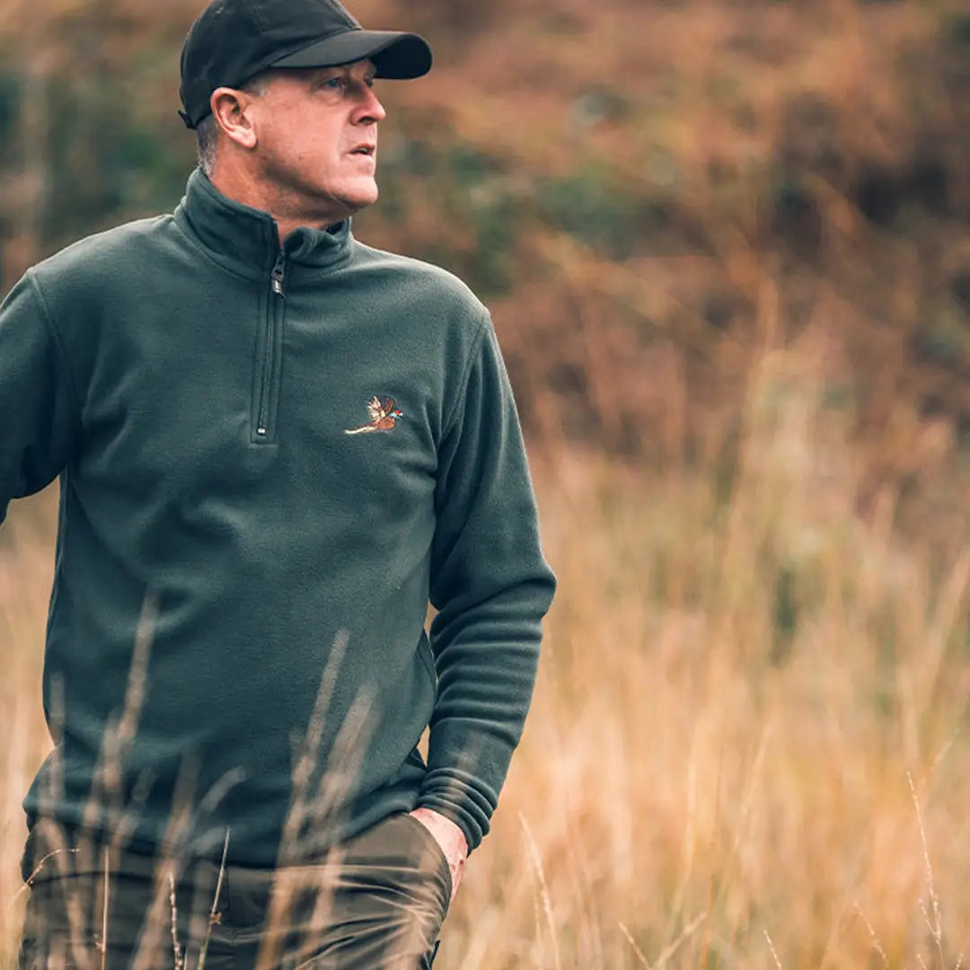 Man in dark green fleece jacket and black cap, sporting the Jack Pyke Pheasant motif